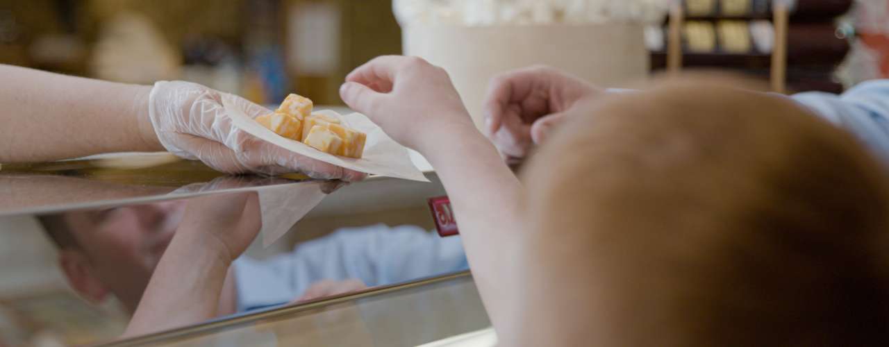 A boy reaching up to grab some free samples of cheese